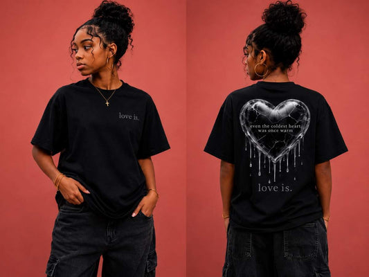 Female model wearing a black oversized healing graphic tee with the "Even the Coldest Heart Was Once Warm" cracked heart design on the back
