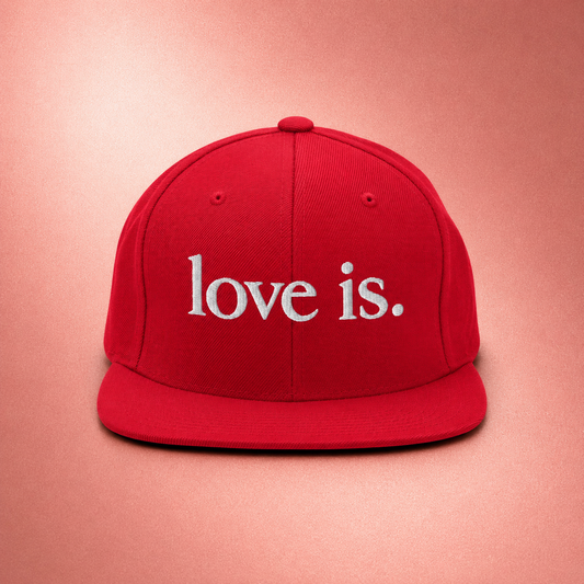 Red snapback hat featuring the embroidered love is. logo on the front. Minimalist Christian streetwear cap designed for everyday wear.