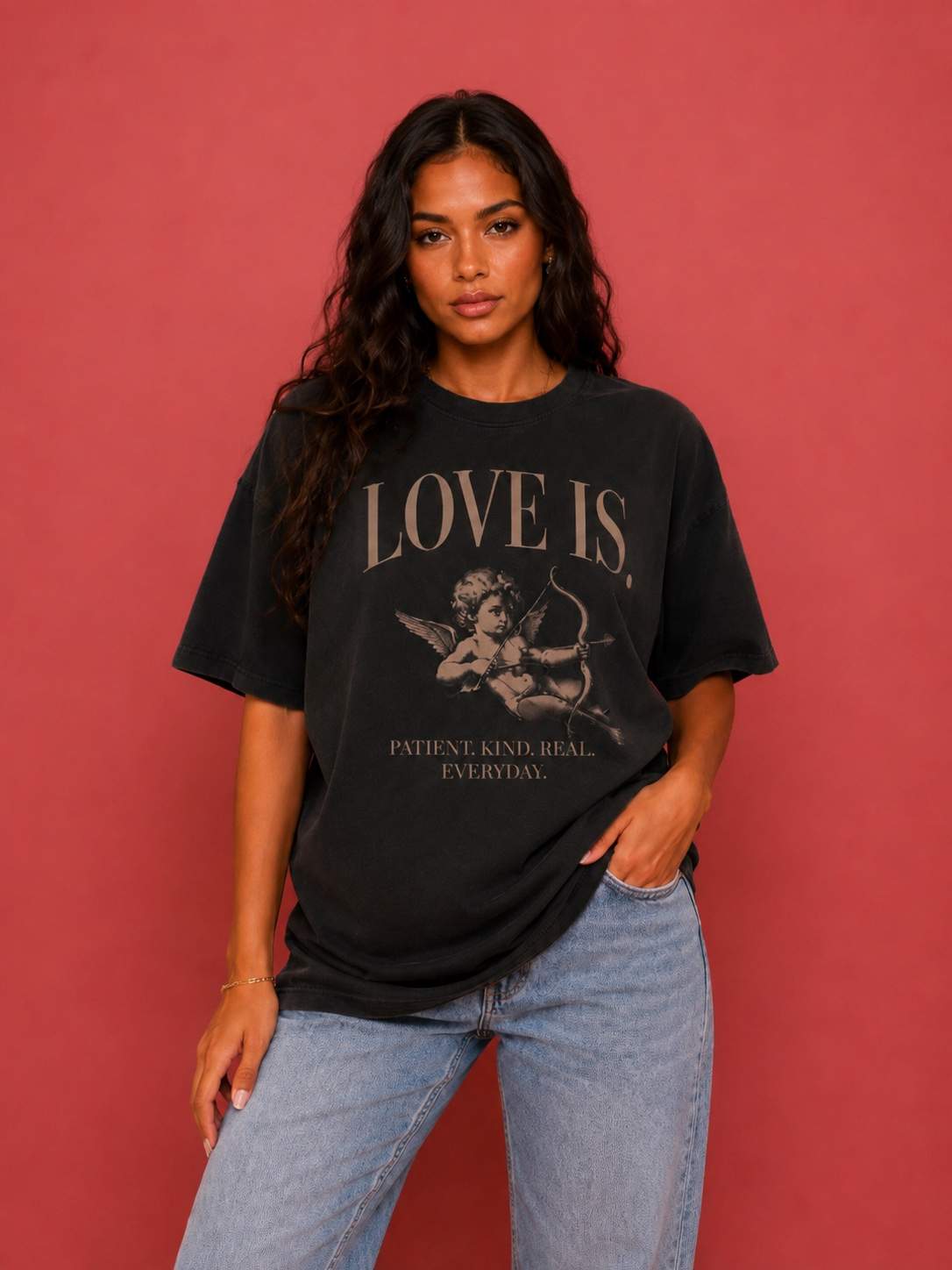 Female model wearing a vintage oversized Cupid graphic tee featuring the "Patient. Kind. Real. Everyday." love is. design